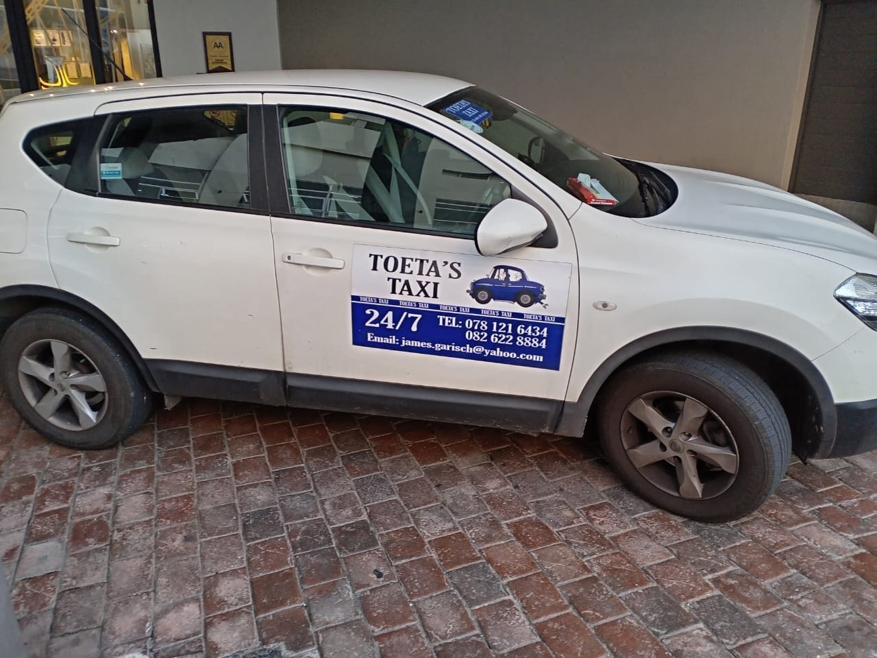 White taxi parked with contact details.